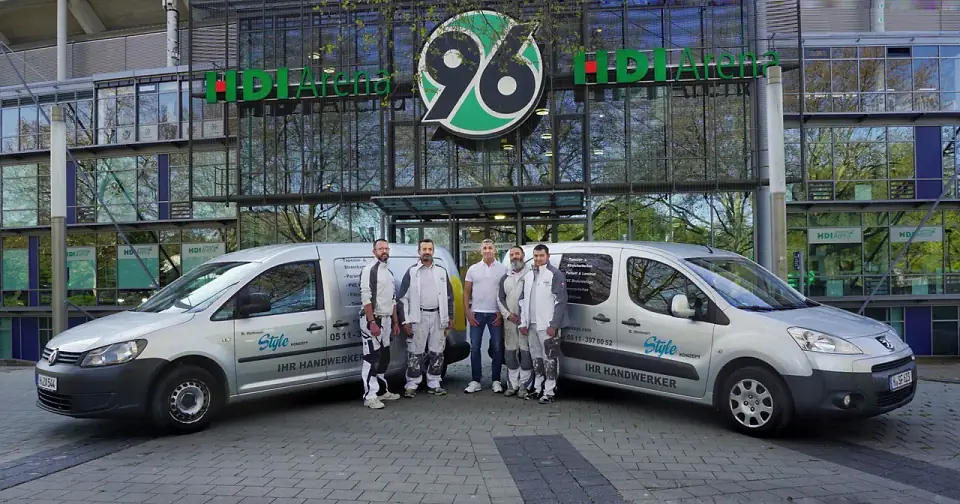Das Team von Stylekonzept mit zwei Firmenfahrzeugen vor der HDI Arena in Hannover