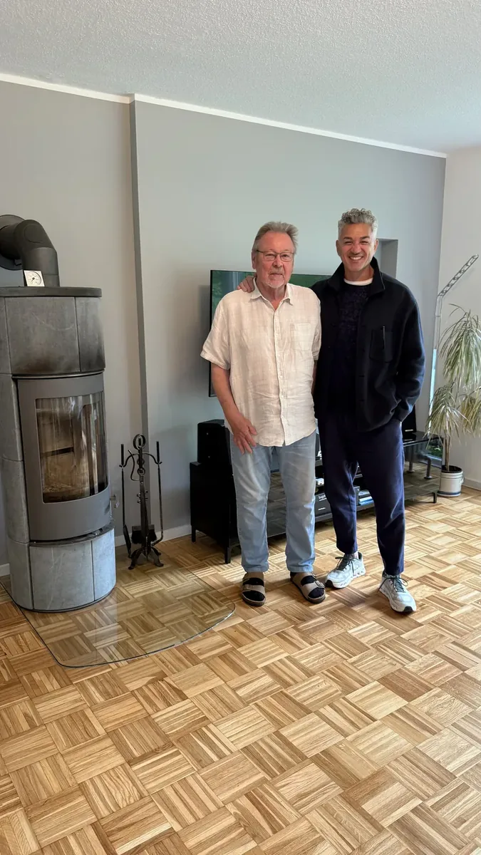 Zufriedener Stylekonzept-Kunde mit Inhaber Raed Hamouri im renovierten Wohnzimmer am Kaminofen